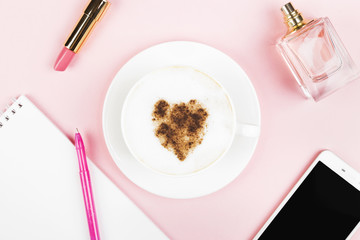 Concept morning planning - cappuccino, notebook, pen, phone, perfume, lipstick on pink background. Feminine and fashion background. Top view