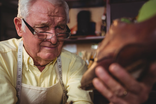 Shoemaker examining a shoe