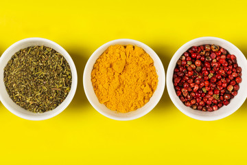 Various spices in bowls on yellow background. Top view. Food background