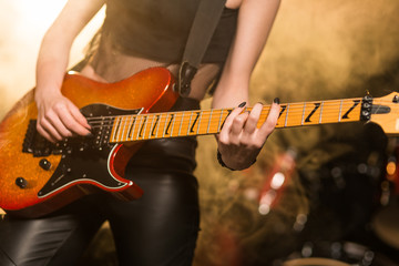 Female hands playing electric guitar close-up
