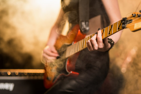 Female guitar player in stage lights