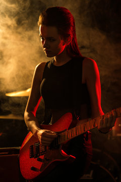 Silhouette of young woman guitar player on stage