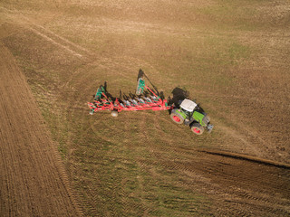 Tractor plowing a agricultural field - aerial view - Tractor cultivating arable land for seeding...