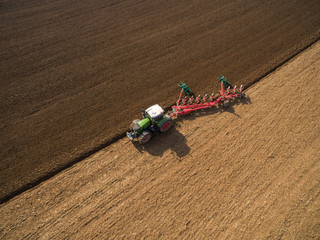 Tractor plowing a agricultural field - aerial view - Tractor cultivating arable land for seeding crops