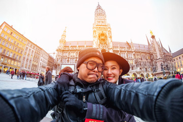 Obraz premium Young Couple Tourists taking selfie with mobile smartphone at the Marienplatz , a famous landmark in Munich, Germany