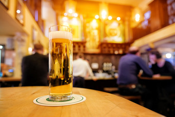 Glass of beer on a wooden bar counter at beer hall in Germany with free space for your text