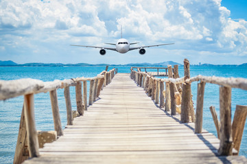 Airplane flying over the wooden bridge in the sea