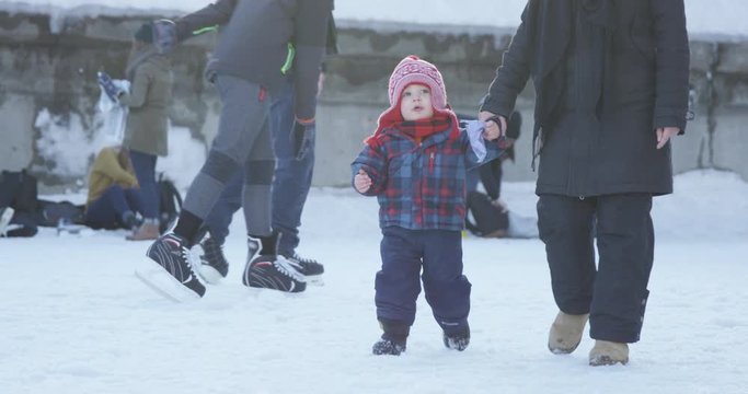 Toddler and mother walk along rideau canal during winter festival - slow motion