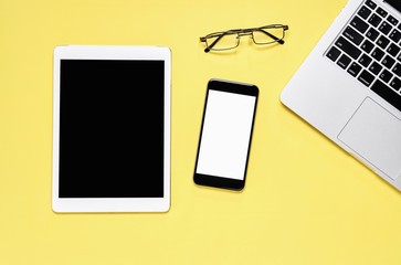 Top view, Modern workplace with tablet with smart phone placed on a pastel yellow background. Copy space suitable for use in graphics.
