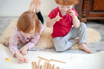 Children draw with pencils lying down and sitting on the floor