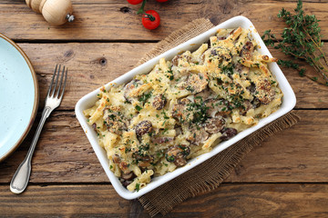 pasta gratinata maccheroni al forno con funghi e formaggio su sfondo tavolo di cucina