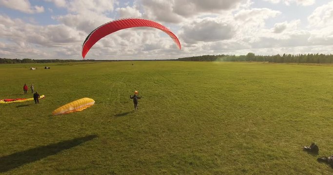 Aerial view of takes off the paraglider with a parachute from the ground on a sunny day.