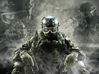 Special forces soldier with guns on gray background.