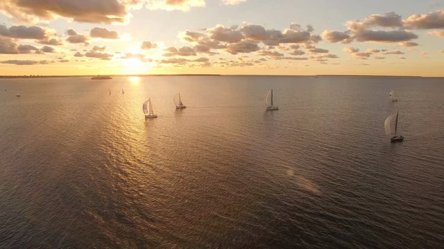 Aerial view of yachts with sails in the sea with a beautiful scenic sunset views. Yachts in the open sea