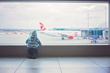 Little child, baby boy, playing at the airport, while waiting for his plane to departure