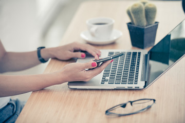 Close up woman hands using smartphone and laptop