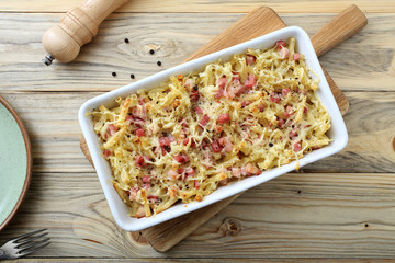 pasta gratinata maccheroni al forno con bacon e formaggio  su sfondo tavolo di cucina