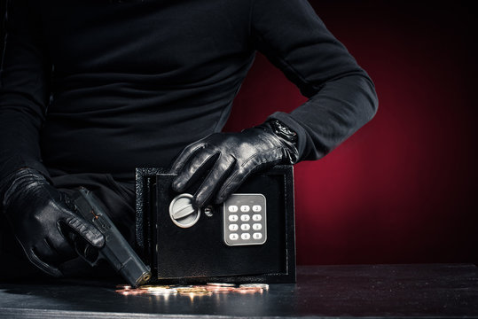 Close-up view of robber with gun taking bitcoin from safe