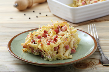 pasta gratinata maccheroni al forno con bacon e formaggio  su sfondo tavolo di cucina
