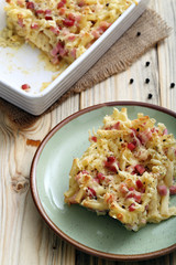 pasta gratinata maccheroni al forno con bacon e formaggio  su sfondo tavolo di cucina