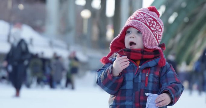 Toddler boy eating healthy snacks at  outdoor winter festival
