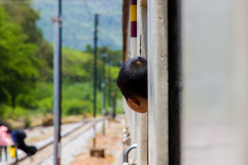 Boy looking out of the ordinary train of the window .view from outside