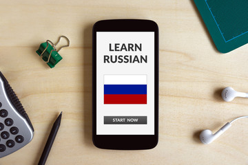Learn Russian concept on smart phone screen on wooden desk. All screen content is designed by me. Flat lay