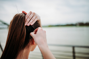 Girl putting bobby pins in hair outdoors. Close-up.