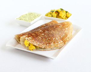 Masala dosa, a south Indian vegetarian, traditional and popular crepe, known globally, with coconut chutney and potato and onion curry, in a tray.