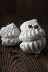 Sweet dessert - vanilla marshmallow (zephyr) on a wooden table with coffee beans, selective focus.