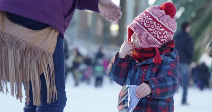 Toddler boy putting snacks in mouth at outdoor winter festival