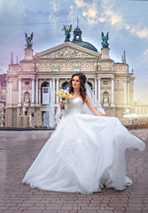 Bride in wedding dress circling in square, in the background of theater, Lviv, Ukraine