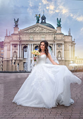 Obraz premium Bride in wedding dress circling in square, in the background of theater, Lviv, Ukraine