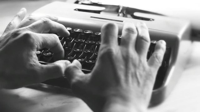  Hands typing a film script or a book on a vintage typewriter, 4k black and white video 