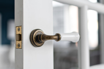 Beautiful modern door knob. Open, wooden front door from the interior of an upscale home with windows.