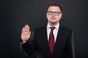 Portrait of business man wearing black suit making oath gesture.