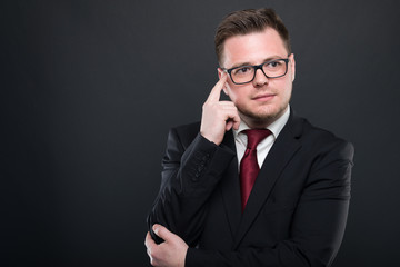 Business man wearing black suit making thinking gesture.