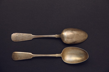 two silver spoons on a dark background