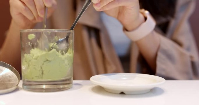 Woman putting wasabi on plate in Japanese restaurant