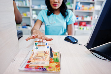 African american pharmacist working in drugstore at hospital pharmacy. African healthcare. Cashier holding money euros.