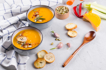 Seasonal fall autumn roasted orange pumpkin carrot soup with ingredients on a table.