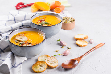 Seasonal fall autumn roasted orange pumpkin carrot soup with ingredients on a table.