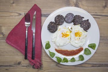 Fried eggs on white plate forming a face.