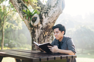 Fototapeta premium Young man studying alone at a park