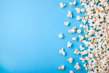 Foto op Aluminium Popcorn scattered on blue background. Copy space for text © adragan