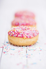 Pink donuts with sprinkles on wooden table