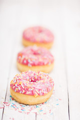 Pink donuts with sprinkles on wooden table