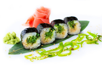 Delicious fresh mini-rolls with algae of Chukka on a banana leaf. Sushi rolls on a white background with ginger and wasabi.