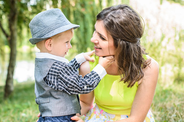 Cute cheerful child with mother play outdoors in park