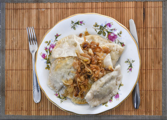 Dumplings with onions on plates, a traditional dish of Polish cuisine.